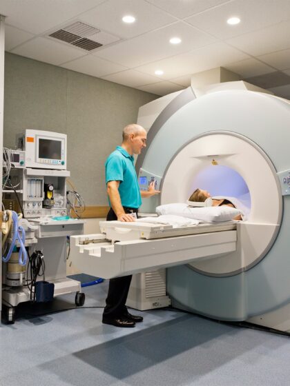 image of a patient going into a ct scan machine with a tech operator beside the patient