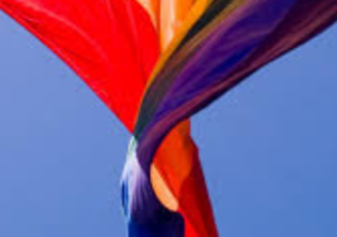image of a rainbow flag against a blue sky background
